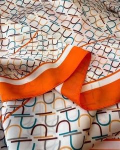 Detail of silk-like scarf featuring geometric Gancini patterns and orange contrast border
