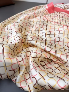 Close-up of smooth geometric silk satin fabric with soft draped folds and subtle sheen