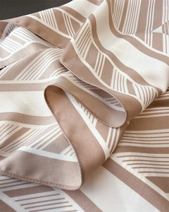 Detailed macro view of the diagonal twill texture and earth-tone geometric silk scarf