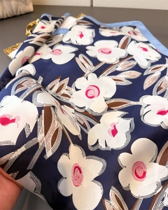 Detailaufnahme eines Seidenschals mit Blumenmuster und rosa Blüten auf dunkelblauem Satin