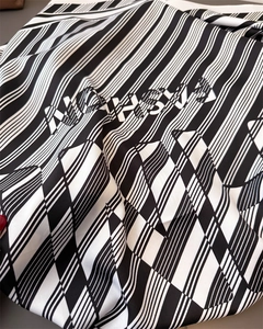 Detailed view of striped silk scarf texture featuring MONSIEUR typography print