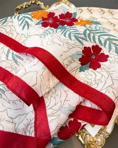 Dettaglio macro di foulard in seta con motivi floreali vintage e trama monogramma F