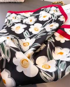 Detailaufnahme des Seidenschals mit Blumenprint, roten Rändern und weißen Blüten