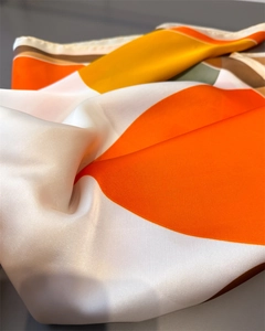 Macro view of geometric satin scarf showing silk texture and fine rolled edge stitching