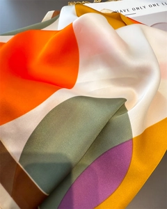 Macro shot of colorful geometric silk scarf showing smooth texture and draped folds