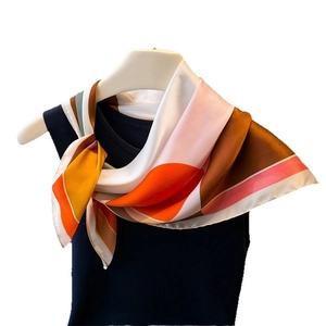 Silk-like square scarf with colorful geometric block patterns worn on neck