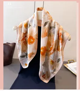 Carré de soie aux imprimés floraux orange présenté sur un cintre minimaliste chic