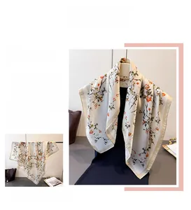 Détail du foulard en satin à motif floral orange avec une bordure dorée champagne