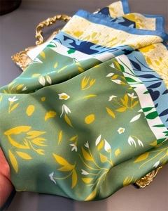 Close-up of a floral silk scarf with green and blue patterns on a golden tray