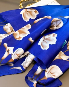 Détail d'un foulard en soie bleu roi aux motifs de lys blancs avec bordures de précision