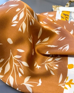 Detailed close-up of floral satin scarf texture with elegant orange and cream foliage pattern