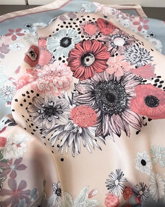 Detailed close-up showing soft peach silk scarf texture with elegant daisy floral patterns
