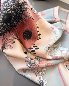 Detail of silk scarf with realistic daisy and sunflower patterns and red rolled edges