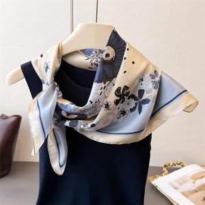 Elegant silk-like scarf with daisy print and polka dots styled on a blue vest