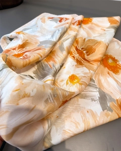 Détail d'un foulard en satin avec imprimés floraux orange et texture soyeuse brillante