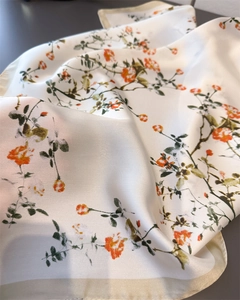 Gros plan sur l'imprimé floral orange d'un foulard carré en satin de soie lisse