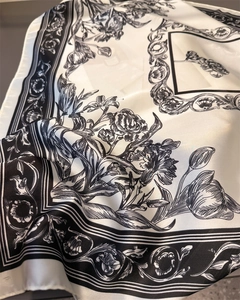 Detail of silk-like satin scarf with elegant black floral prints and soft fabric folds