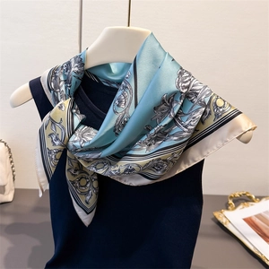 Floral satin silk scarf with baroque lily patterns draped on a blue knit top