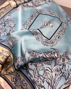 Detail of silk-like scarf featuring elegant black floral patterns on light blue fabric