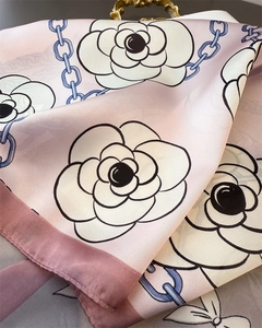 Detail of pink silk scarf with camellia flower pattern and blue chain motifs on satin fabric