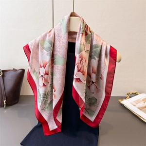 Elegante sciarpa in seta rosa con stampa a pivoine e bordo rosso su supporto espositivo