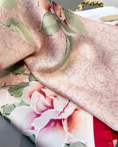 Dettaglio di un foulard in seta rosa con stampa di peonie e motivi geometrici