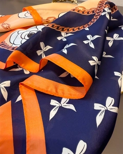 Detailed macro view of navy blue silk scarf with chain print and white camellia pattern