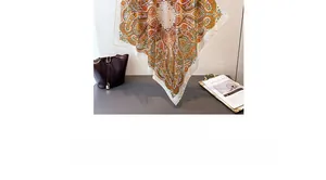 Detailed view of white paisley silk scarf with orange patterns draped over an office desk