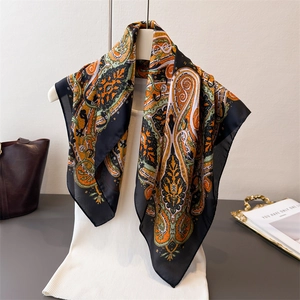 Exotic paisley silk-feel scarf with vibrant orange and green patterns on display