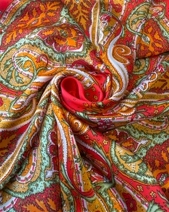 Macro detail of silk scarf with paisley patterns in orange and red satin fabric