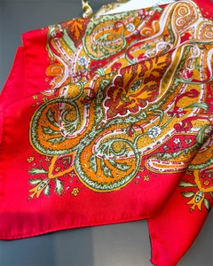 Macro shot of red paisley silk scarf showing smooth texture and detailed exotic patterns