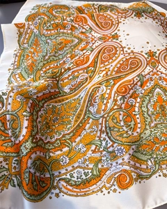 Detailed macro view of ivory silk scarf with vibrant orange and green paisley patterns