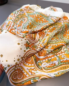 Detail of silk-like scarf with orange and green paisley print and soft texture