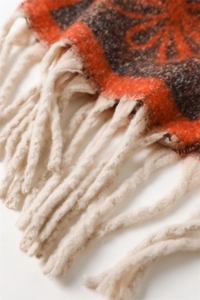 Detailed macro view of orange and grey jacquard knit scarf with thick cream fringe tassels