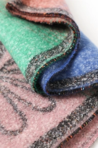 Close-up of thick floral cashmere shawl featuring pink green blue gradient and fringe