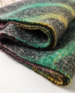Close-up of rainbow plaid cashmere-feel scarf showing thick knitted texture and soft tassels