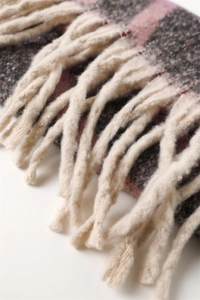Detail of pink and grey rainbow plaid scarf showing thick twisted tassels and soft knit texture