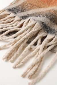 Close-up of soft cashmere-like scarf with rainbow plaid patterns and elegant fringe details