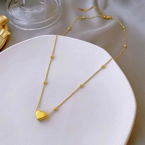 Minimalist 18k gold heart pendant necklace with beaded chain on elegant decor