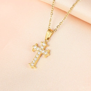 Macro detail of gold cross pendant featuring brilliant zircon stones and vintage engraving