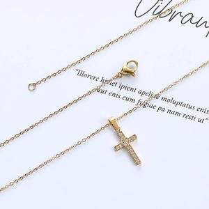 Detail of gold cross pendant necklace with zircon heart inlay on artistic white card