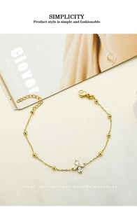 Close-up of golden four-leaf clover bracelet with zircon stones on a stylish fabric background
