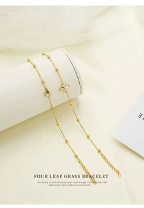 Detail of clover bracelet with zircon inlay on white display stand, golden stainless steel