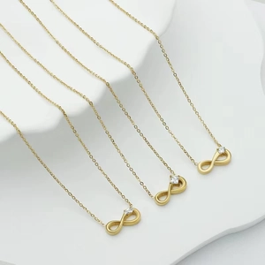 Three gold infinity necklaces with zircon stones on white display tray