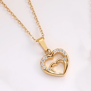 Dettaglio macro della collana con pendente a doppio cuore dorato e zirconi lucidi