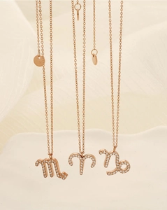 Détail de pendentifs signes du zodiaque en or rose avec cristaux pavés sur plateau