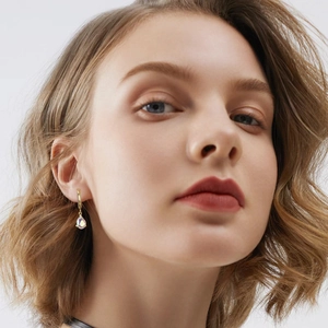 Detail of gold teardrop earrings with iridescent crystals worn by a female model
