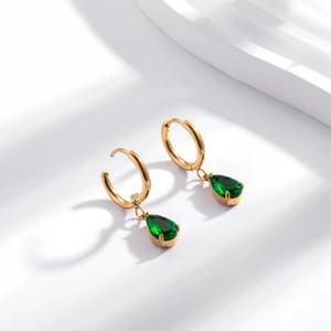 Close-up of gold stainless steel hoop earrings with faceted green teardrop zircon pendants
