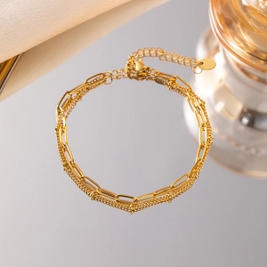 Détail d'un bracelet double couche doré avec breloque logo sur support réfléchissant