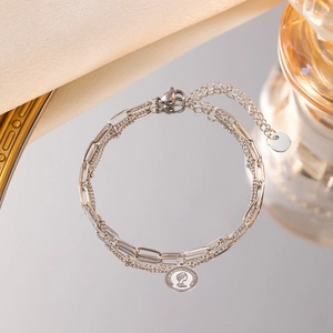 Détail du bracelet double chaîne en argent avec une breloque pièce de la reine Elizabeth